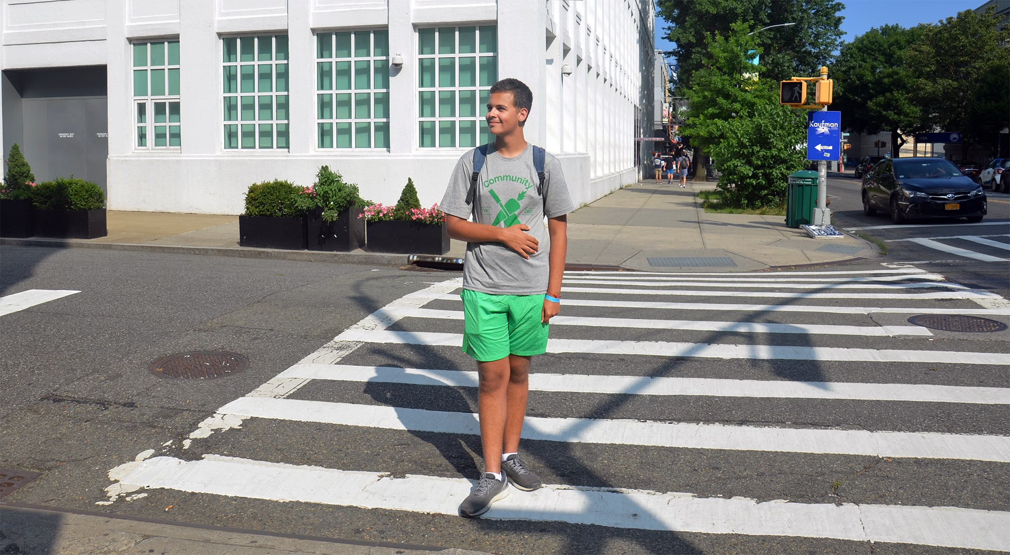 A boy wearing a Community Gardening tee-shirt crosses the street in Astoria, Queens
